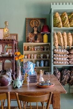 a wooden table sitting in front of a shelf filled with baskets and vases on top of it