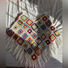 a crocheted granny blanket with fringes on top of it, sitting on a bed