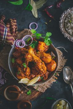 a bowl filled with chicken next to rice and other food on a wooden table top