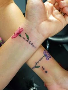 two people holding hands with tattoos on their wrists and one has a flower in the middle