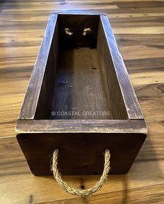 a wooden box sitting on top of a hard wood floor with rope around the bottom