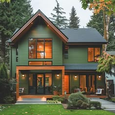 a large green house with lots of windows on the front and side of it, surrounded by trees