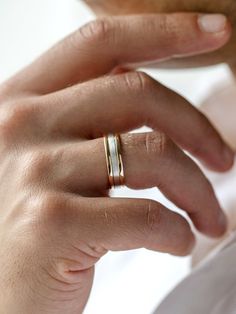 a person wearing two different rings on their fingers and one is holding the other hand