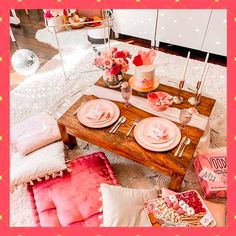 the table is set with pink and white plates, silverware, flowers and candles