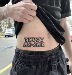 a man is holding his stomach with the words trust no one written in black ink