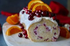 an orange and cranberry roll on a marble platter surrounded by sliced oranges