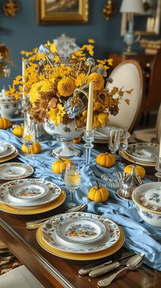 the table is set with yellow flowers and silverware on it, along with other dishes