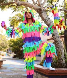 a man in a colorful costume standing next to a tree