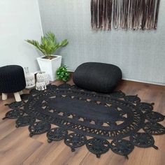 a black rug sitting on top of a wooden floor next to a potted plant