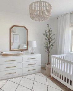 a baby's room with white furniture and a chandelier hanging from the ceiling