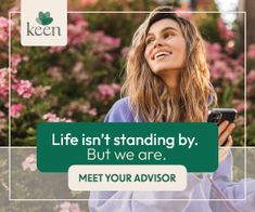 a woman standing in front of pink flowers holding a cell phone and looking up at the sky