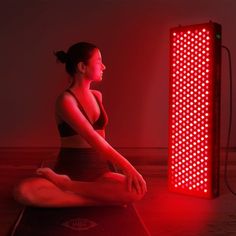 a woman sitting on the floor in front of a red light