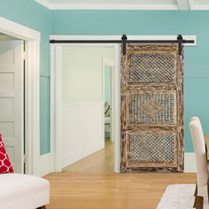 a living room with blue walls and white furniture in front of an open door that leads to the dining area