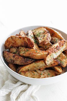 a white bowl filled with fried potatoes on top of a table