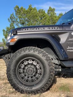 the jeep is parked on the side of the road in the field with trees behind it