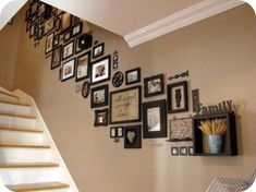 a staircase with many pictures on the wall and framed photos hanging up against the wall