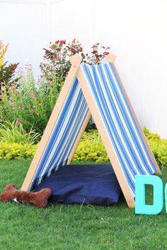 a teepee tent sitting in the grass next to a dog bed