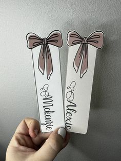 someone holding up two bookmarks that say happy mother's day and one with a bow