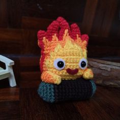 a crocheted stuffed animal with big eyes sitting on top of a wooden table