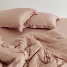 an unmade bed with pink sheets and pillows