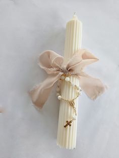 a white candle with a ribbon tied around it and some charms on the top of it