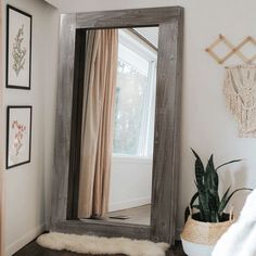 a mirror sitting on top of a wooden table next to a potted plant in front of a window