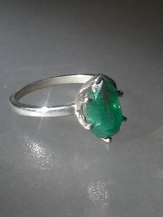 Imperfectly Perfect! This emerald came from a huge lot acquired in the late 70s. The natural inclusions in this stone along with the faceting on the back of the emerald make this ring so unique. This natural 1.56ct emerald is pear shaped cut and pavilion set (back of the stone is set face up). There is a natural clarity characteristic towards the lower tip of pear. Sterling silver mounting has five prongs and a v tip to protect the point of pear. High polished finish band tapers from 1.7 to 1.5 Vintage Emerald Ring With Prong Setting, Green Pear-shaped Emerald Gemstone Ring, Green Pear-shaped Emerald Ring, Emerald Cut Emerald Gemstone In Prong Setting, Elegant Untreated Green Emerald Ring, Emerald Cut Emerald Gemstones With Prong Setting, Oval Emerald Gemstone For May Birthstone, Formal Faceted Emerald Ring, Pear-shaped Emerald Ring For May Birthstone With Prong Setting