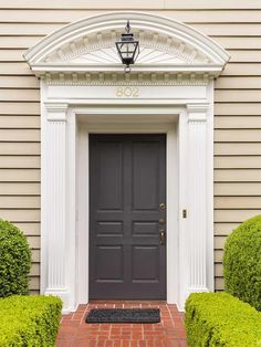 the front door is flanked by two topiary bushes