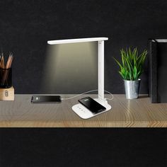 a desk with a cell phone, laptop and other items on it next to a lamp