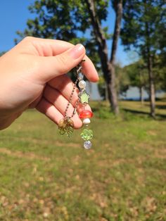 a person is holding onto some beads in their hand and there are trees in the background