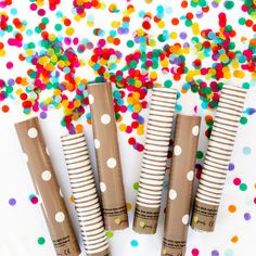 four brown and white polka dot paper straws on a table with confetti