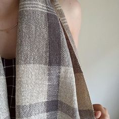 a close up of a person wearing a brown and white checkered scarf over their shoulders