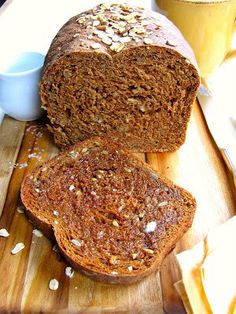 two loaves of bread sitting on top of a cutting board next to a cup of coffee