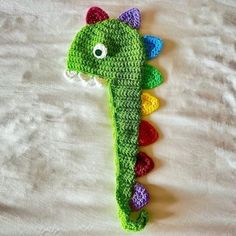 a crocheted seahorse is laying on a white sheet with its head turned to the side