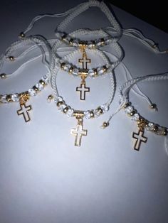 four necklaces with cross charms on them sitting on a white table next to each other