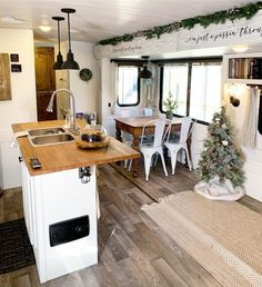 the kitchen is decorated for christmas with white chairs and wood counter tops, along with a small tree