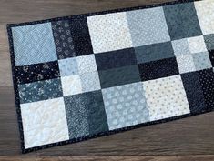 a black and white patchwork table runner on a wooden surface with a wood floor