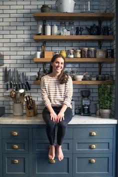 a woman sitting on top of a kitchen counter