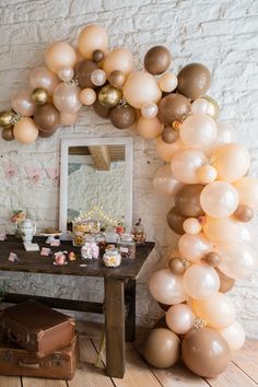 a table topped with balloons in front of a white brick wall next to a mirror