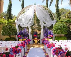 an outdoor wedding setup with white drapes and purple flowers