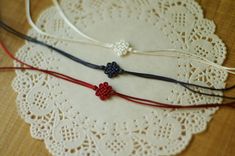 three bracelets with red, white and blue beads are sitting on a doily