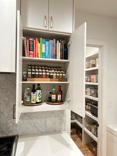 a kitchen with white cabinets and shelves filled with spices