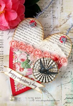 a heart shaped card with flowers on it next to a pink flower and a ribbon