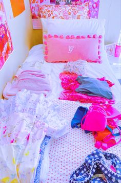 an unmade bed with lots of clothes on it