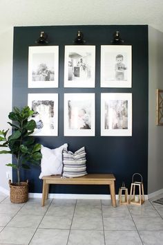 a living room with pictures hanging on the wall and a bench in front of it