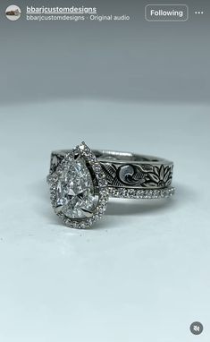 a white gold ring with an oval cut diamond in the center and intricate filigrees around the band