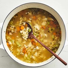 a bowl of soup with noodles, carrots and broccoli