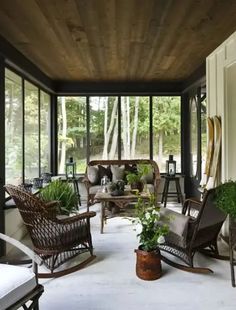 a living room filled with lots of furniture and plants on top of the floor next to windows