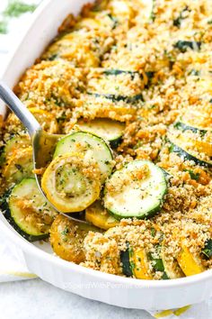 a casserole dish filled with zucchini, cheese and bread crumbs