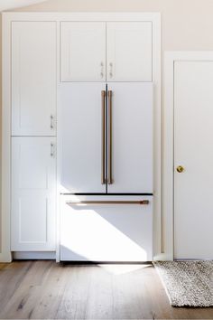 a white refrigerator freezer sitting inside of a kitchen next to wooden floors and cabinets